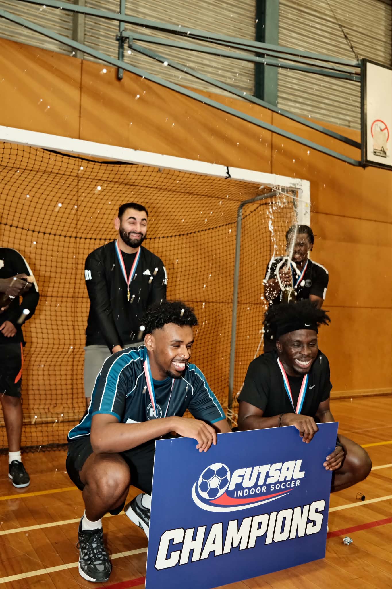 Players laugh behind the champions board as a teammate sprays a bottle in celebration.